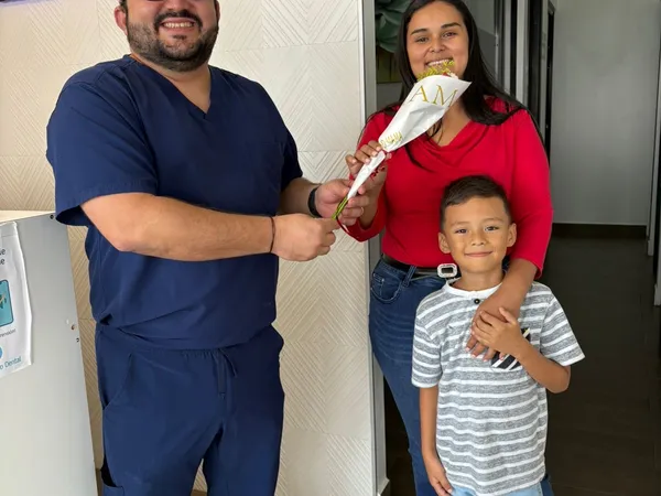 Odontólogo entregando flores a una familia en Centro Estético Dental