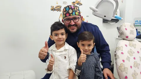 Odontopediatra con dos niños en un consultorio dental infantil